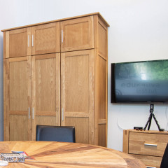 Ein gemütlicher Besprechungsraum mit Holztisch, Stühlen, einem Schrank und einem Fernseher an der Wand.